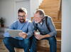 Older man and man looking at tablet on stairs